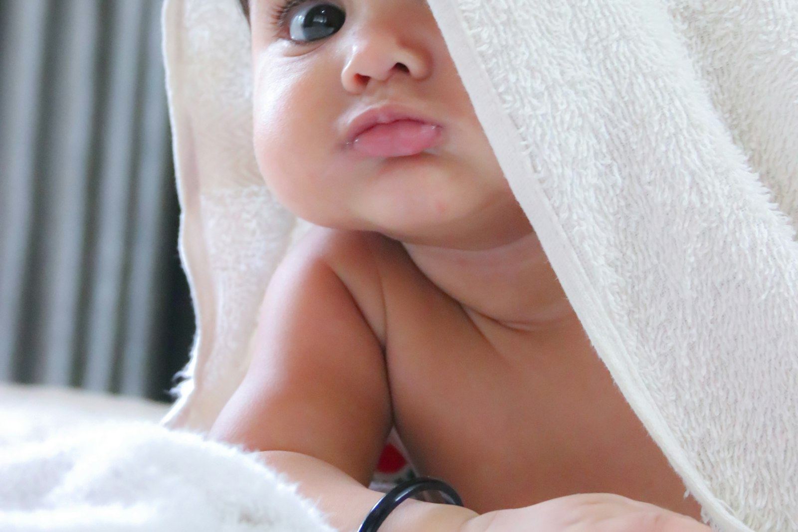 Baby peeking out from a white hooded towel after a bath