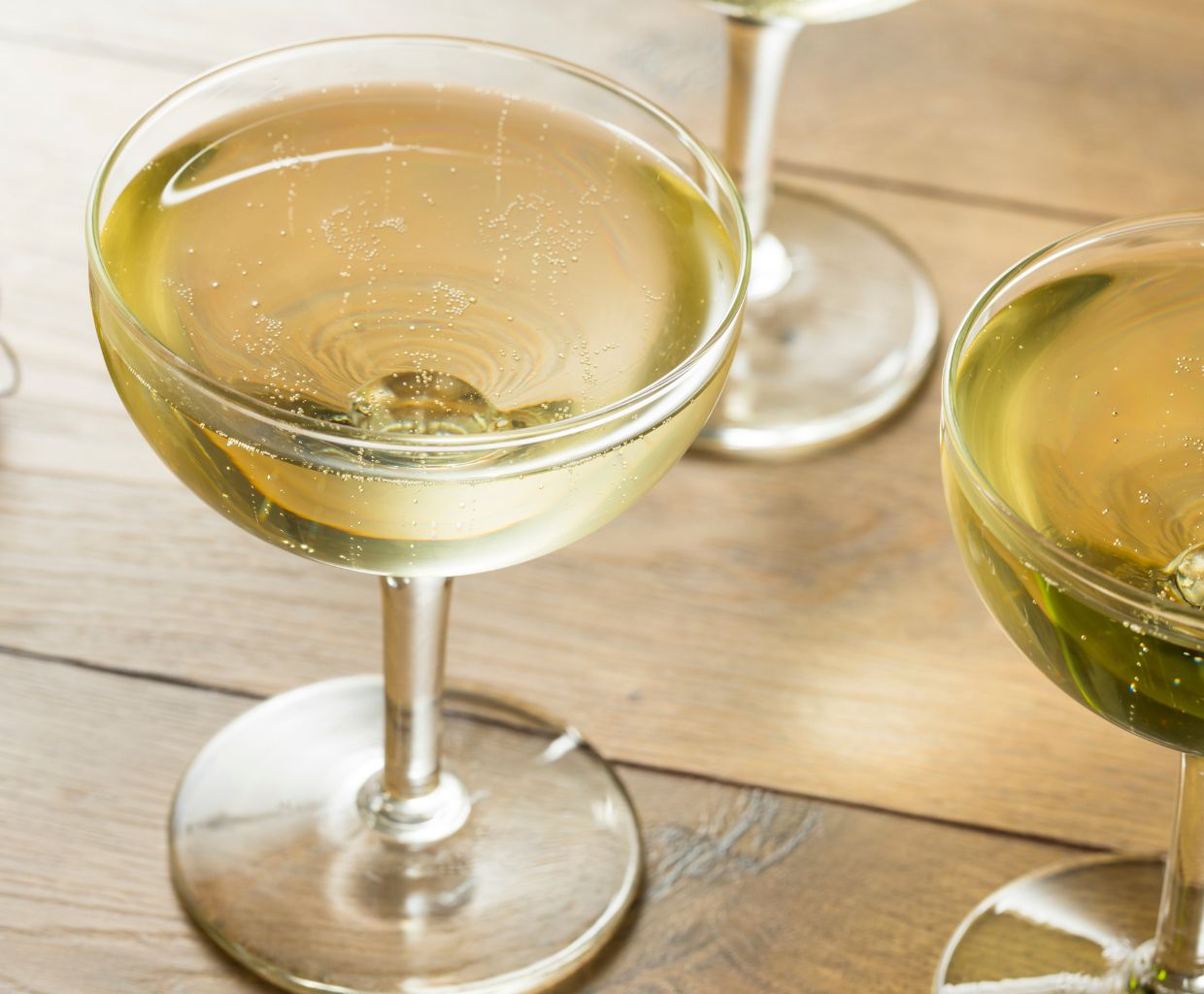 Two coupe glasses of sparkling wine on a wooden table