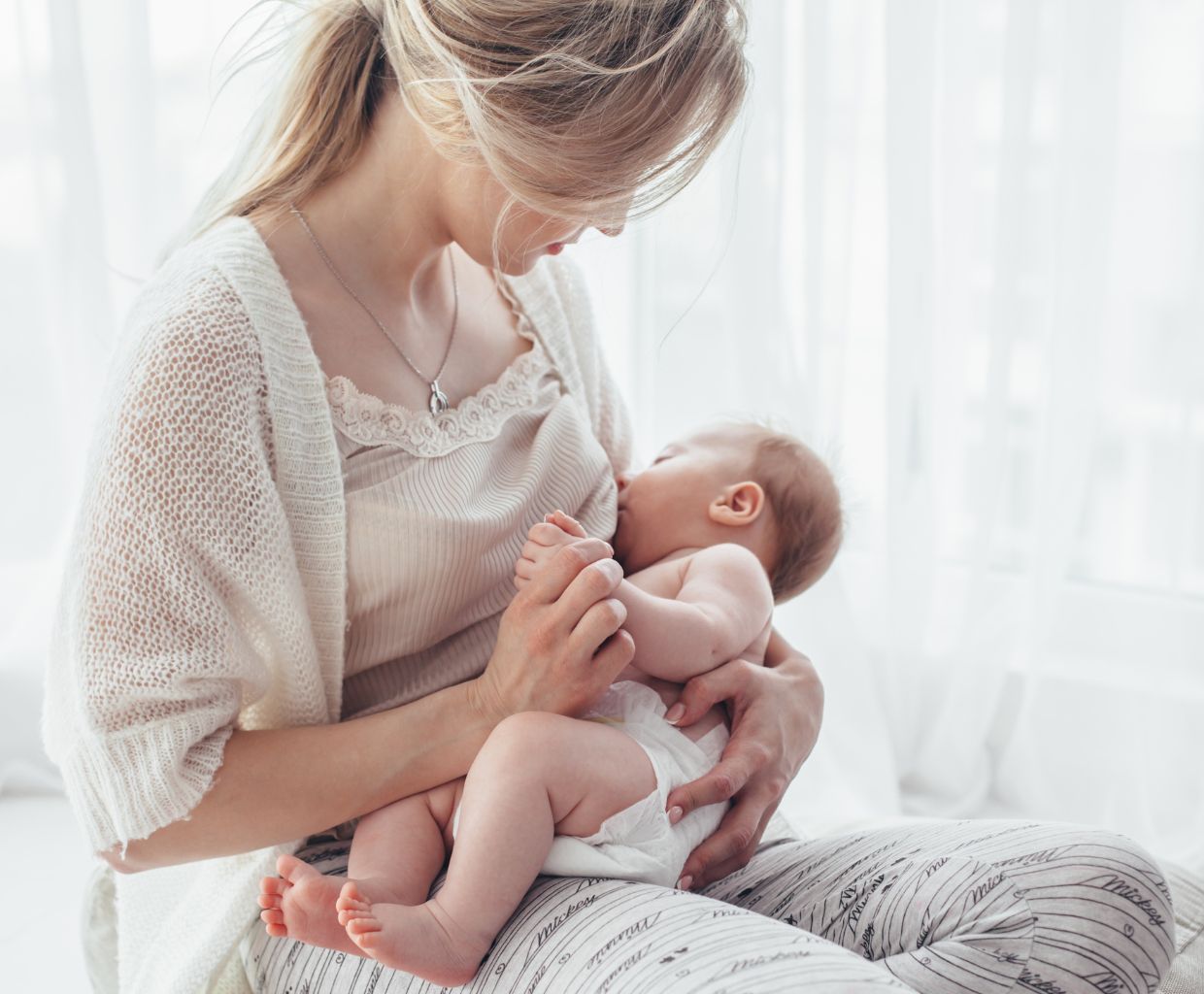 Mother sitting cross-legged on the floor breastfeeding her baby in a cradle hold