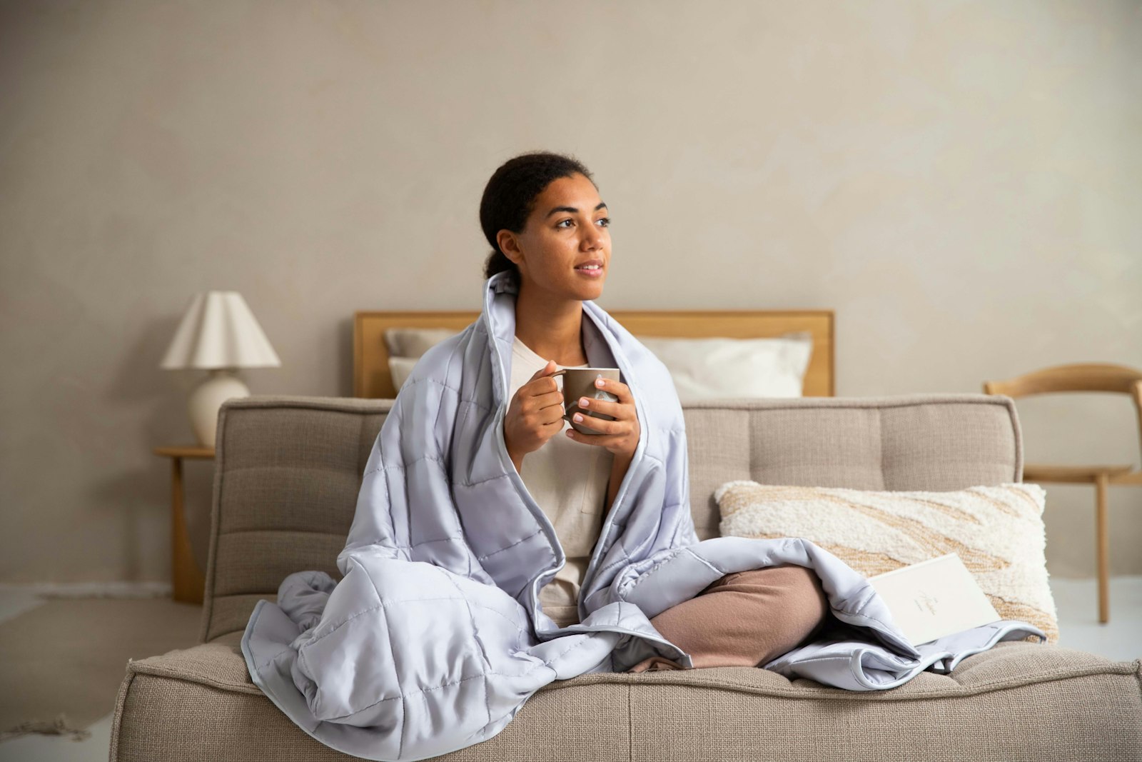 Woman wrapped in a blanket on a sofa, holding a warm mug