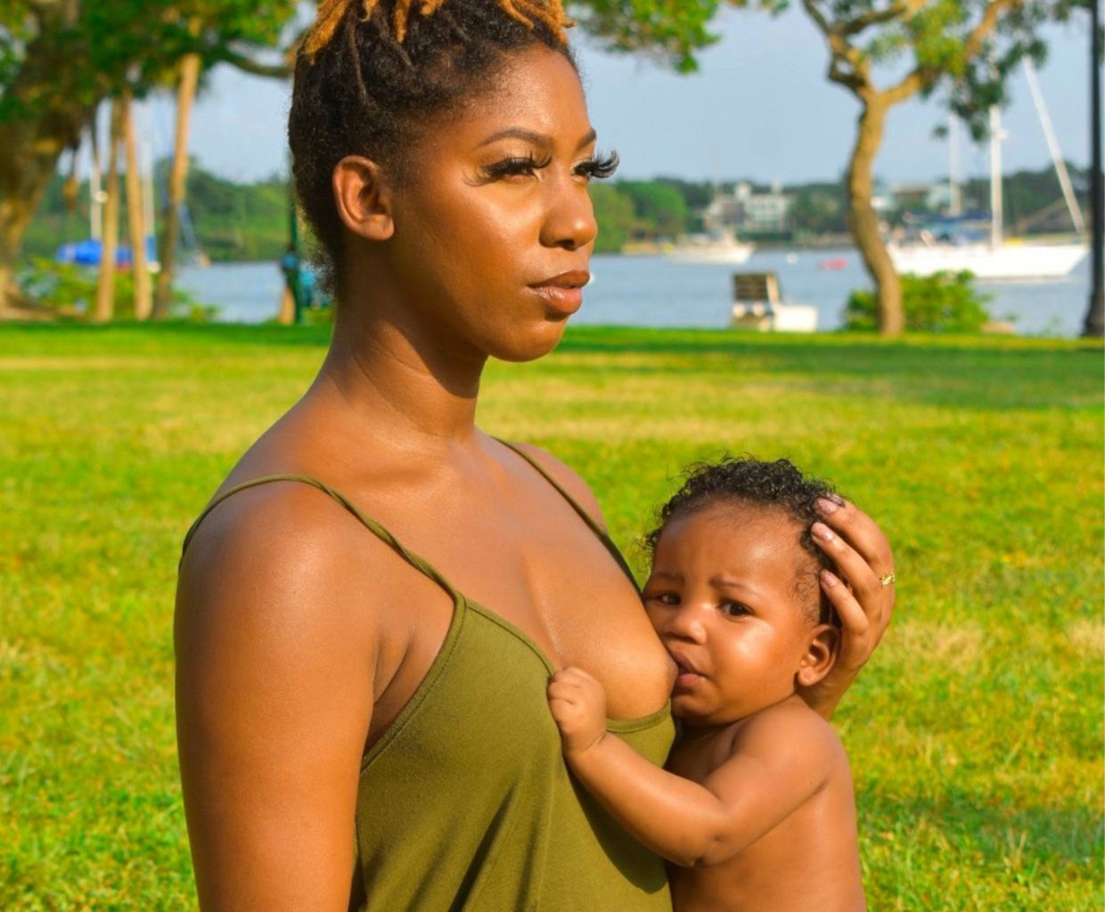 Mother breastfeeding her baby outdoors in a sunny park