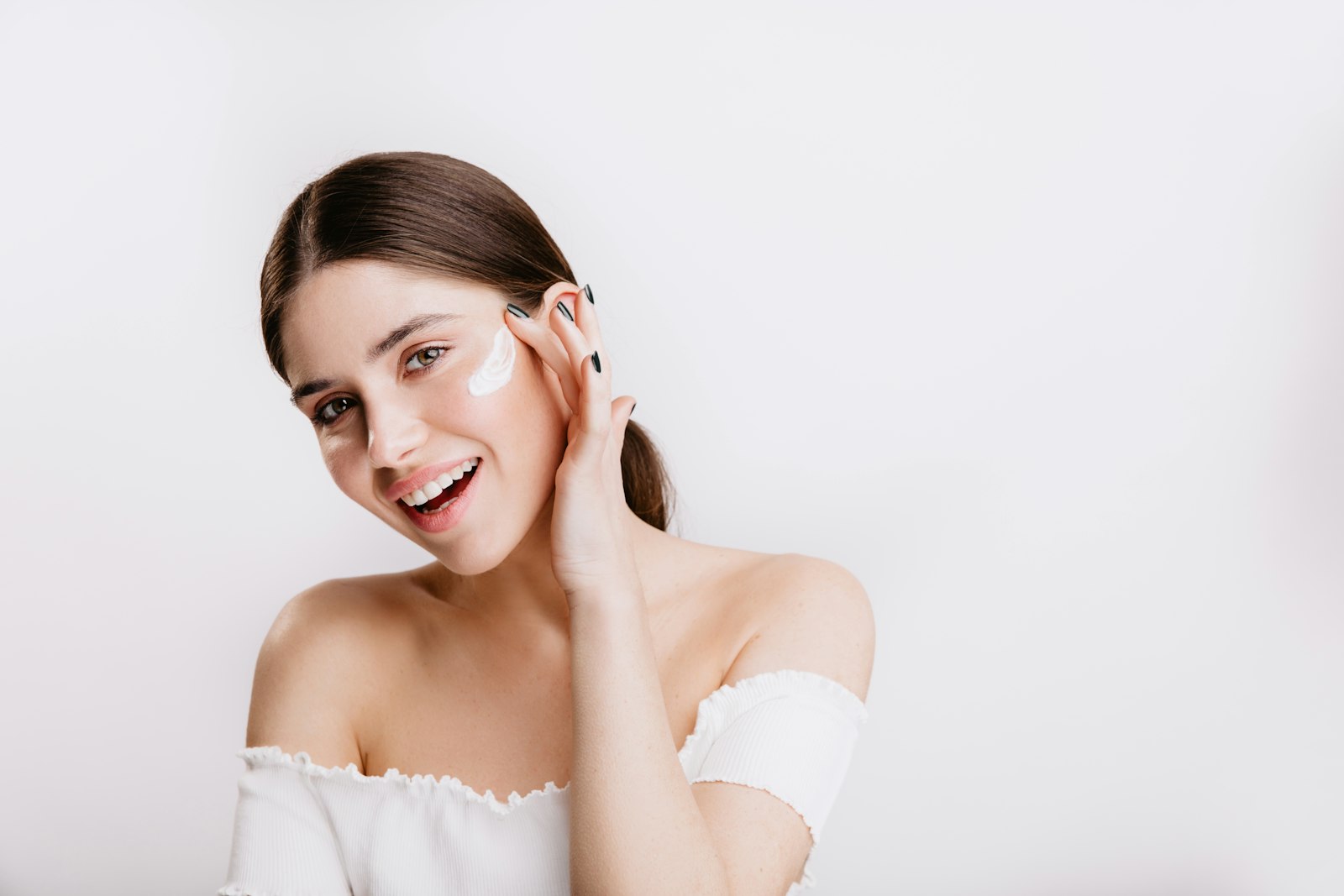 Smiling woman touching her cheek with a dab of face cream