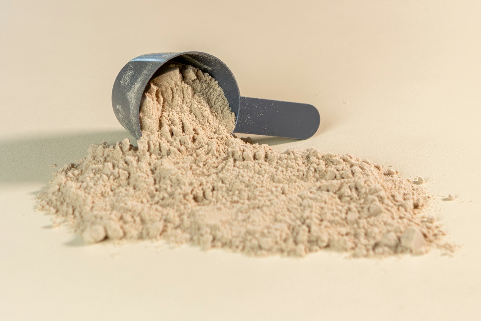Scoop of supplement powder spilling onto a table