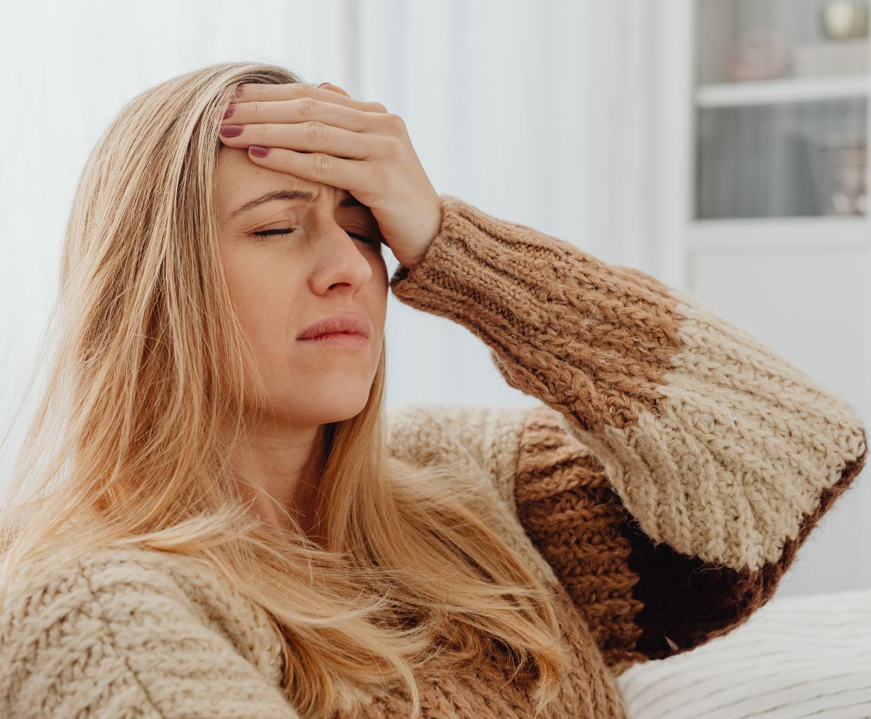 Woman sitting on a sofa holding her forehead with a headache