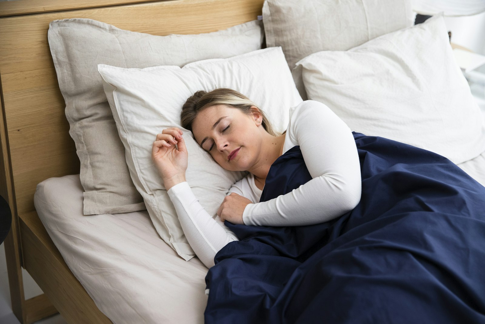 Woman asleep in bed under a dark blue blanket