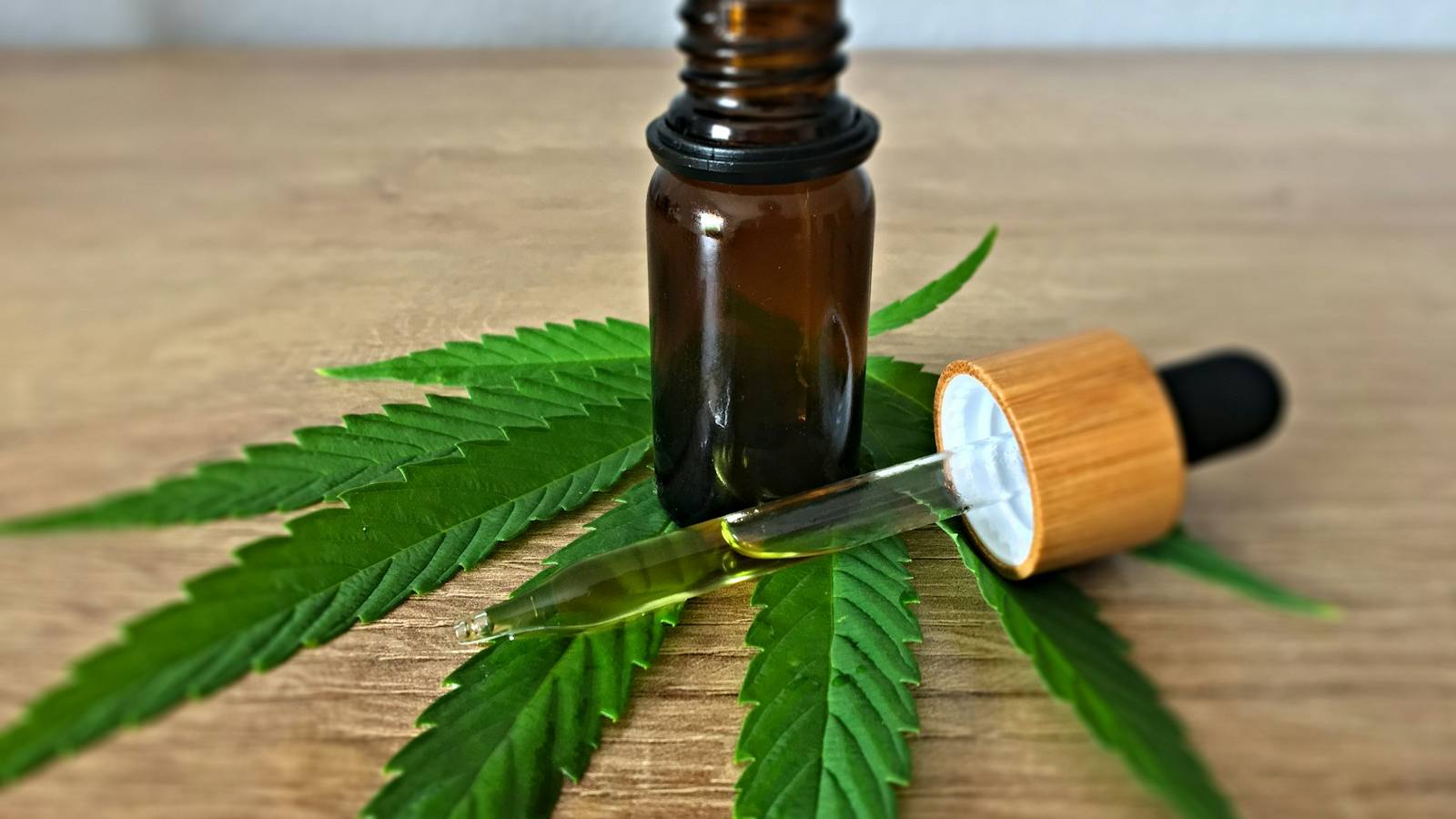 Amber dropper bottle of oil lying on a cannabis leaf