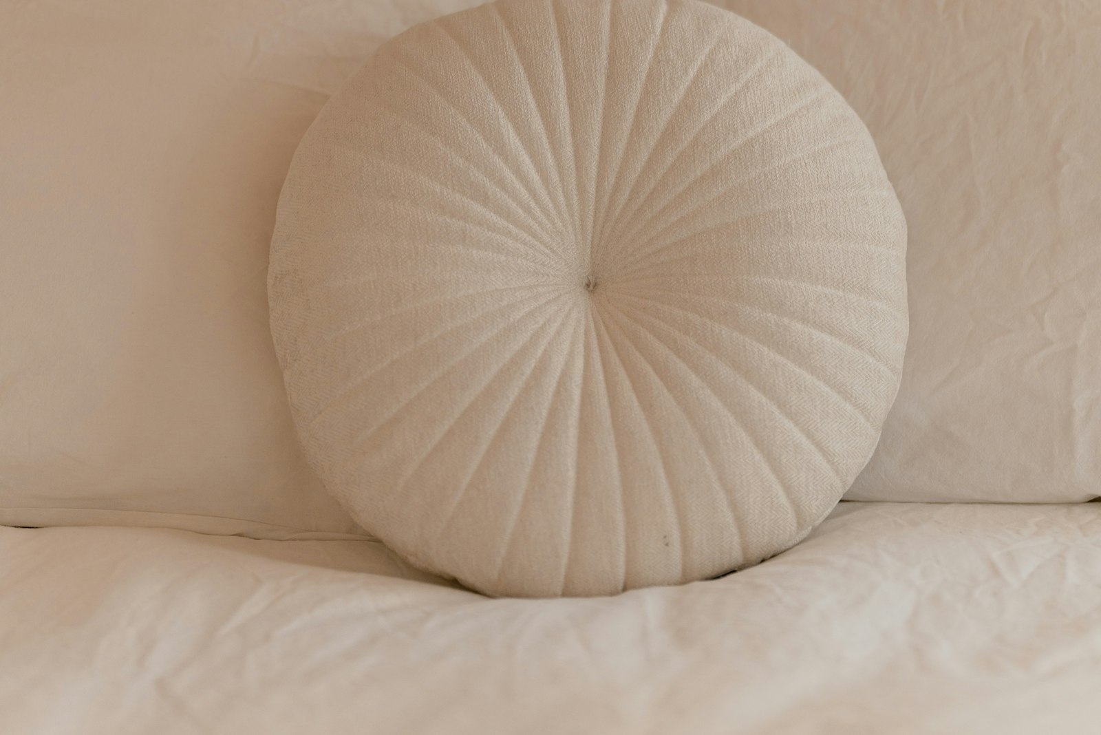 White round cushion on a white bed