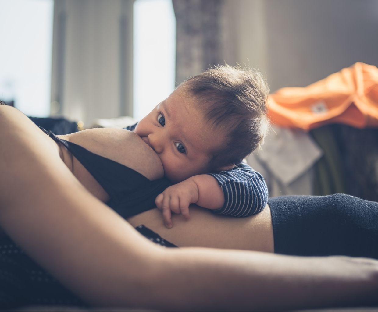 Baby breastfeeding while lying on a reclining parent’s body in a laid-back position