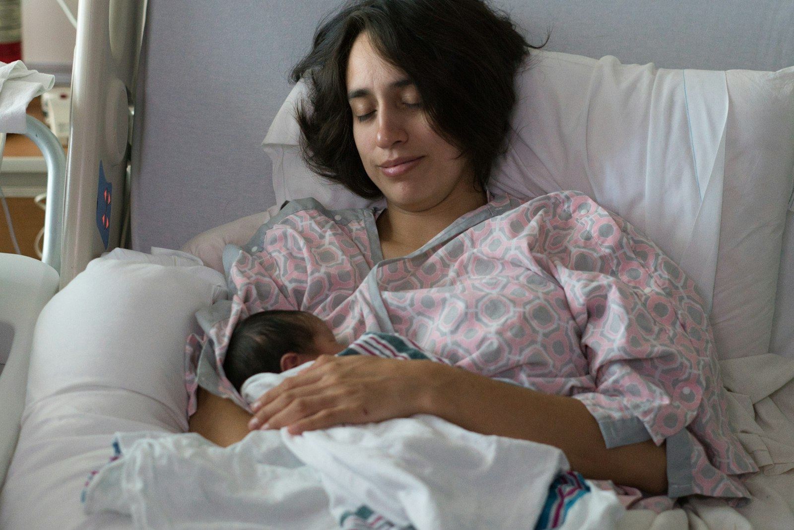 Mother in a hospital gown holding her newborn skin to skin