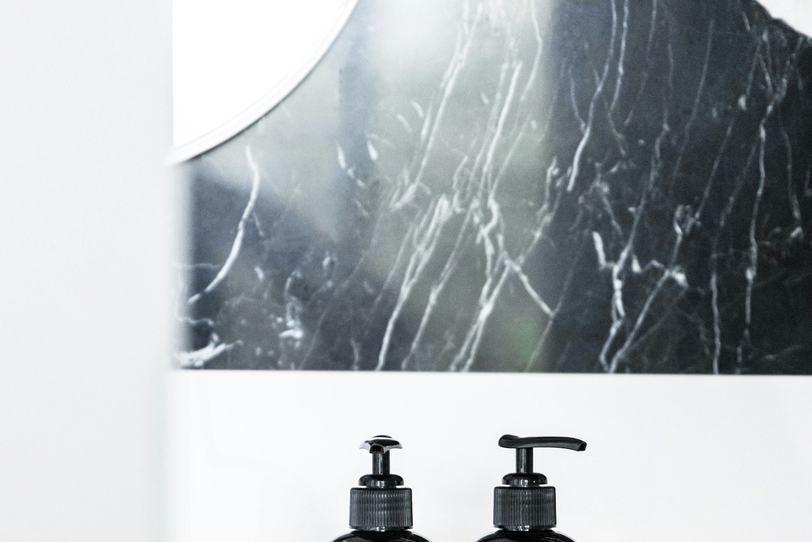 Two pump bottles on a bathroom counter under a mirror