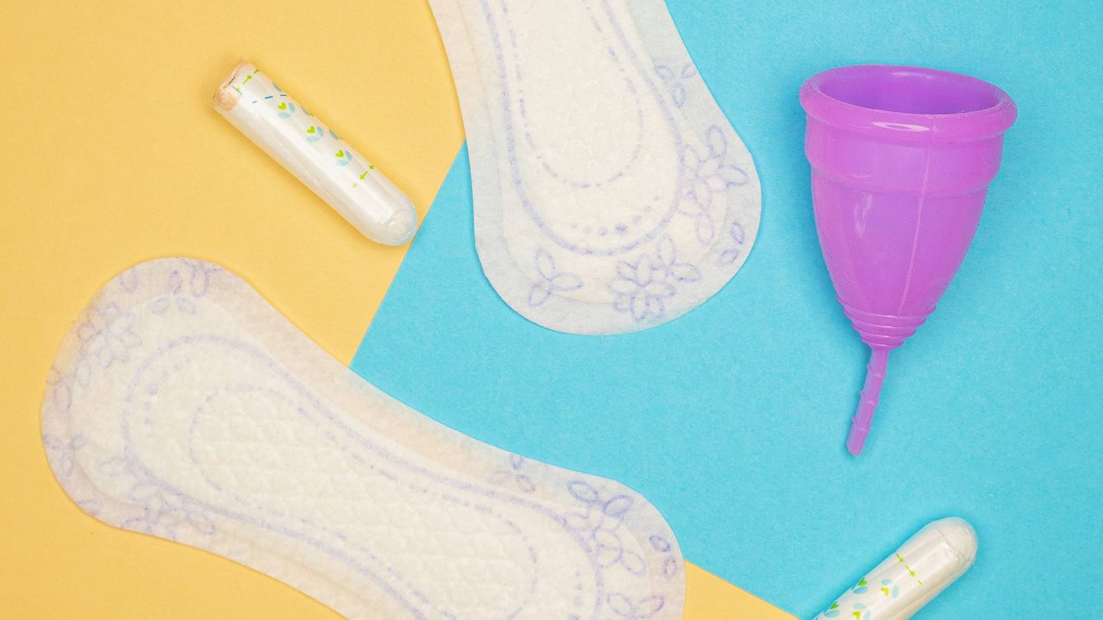 Sanitary pads, tampons and a menstrual cup on a colorful background