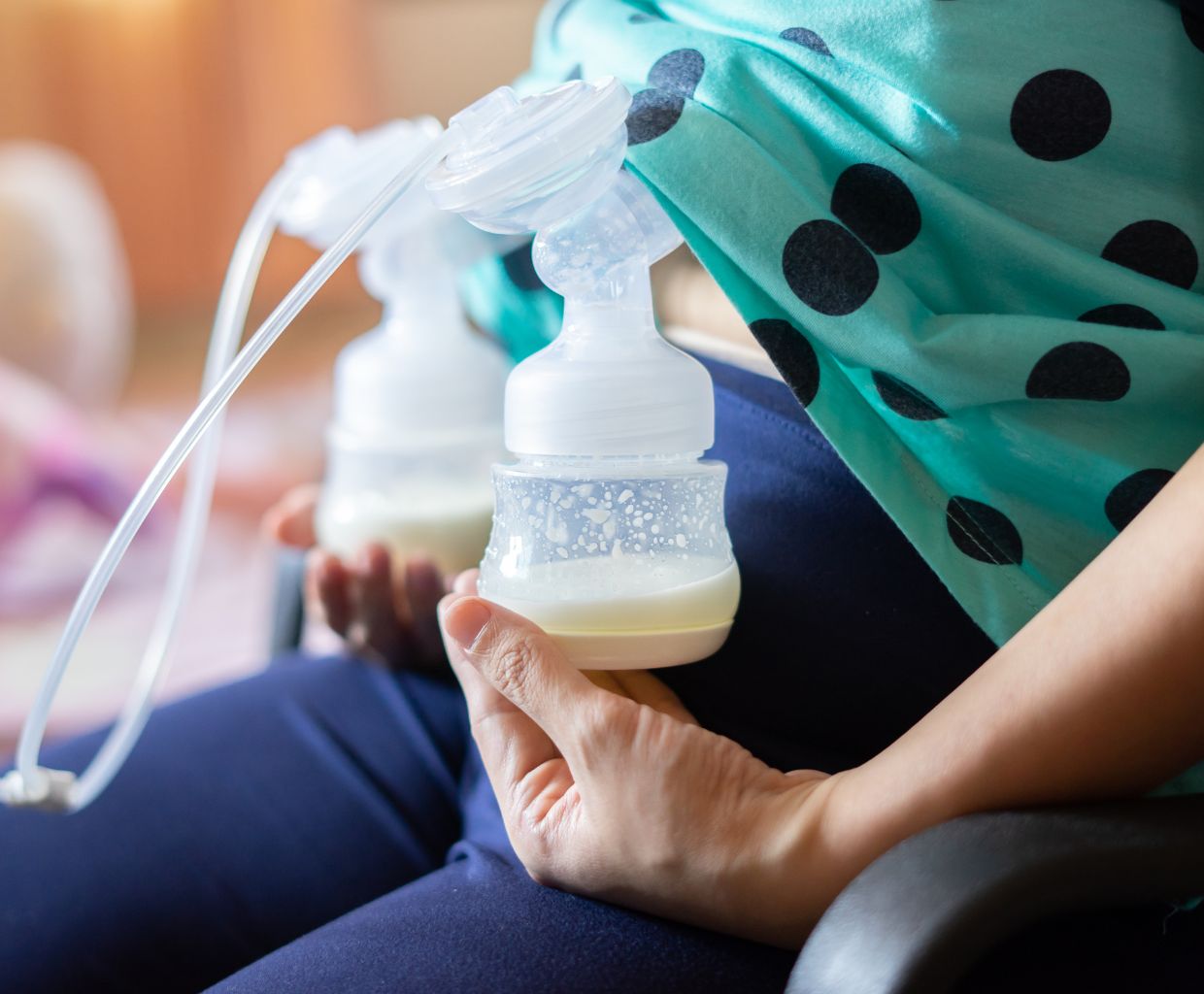 Close-up of a mother holding a breast pump bottle with freshly expressed milk