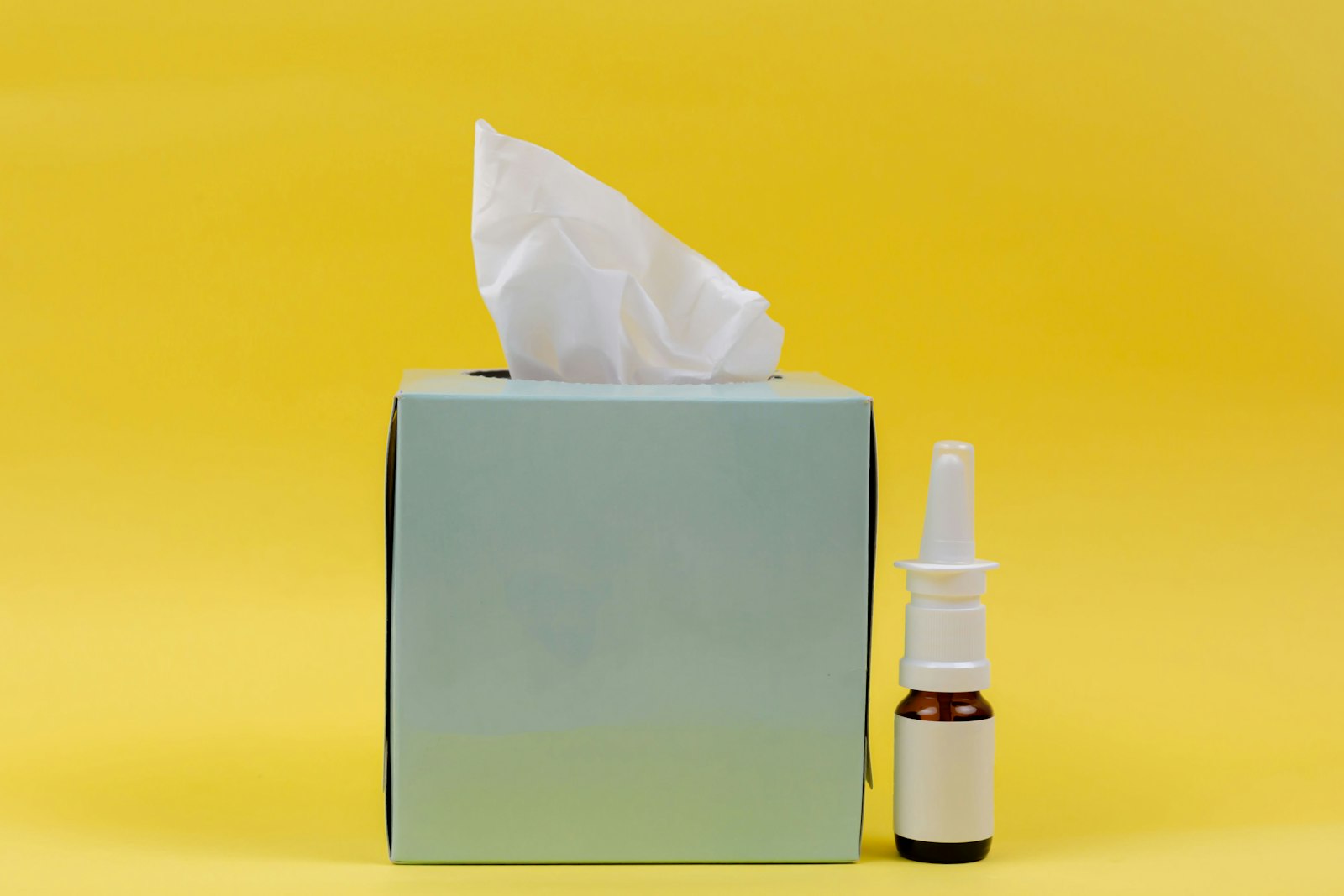 Box of tissues next to a nasal spray bottle