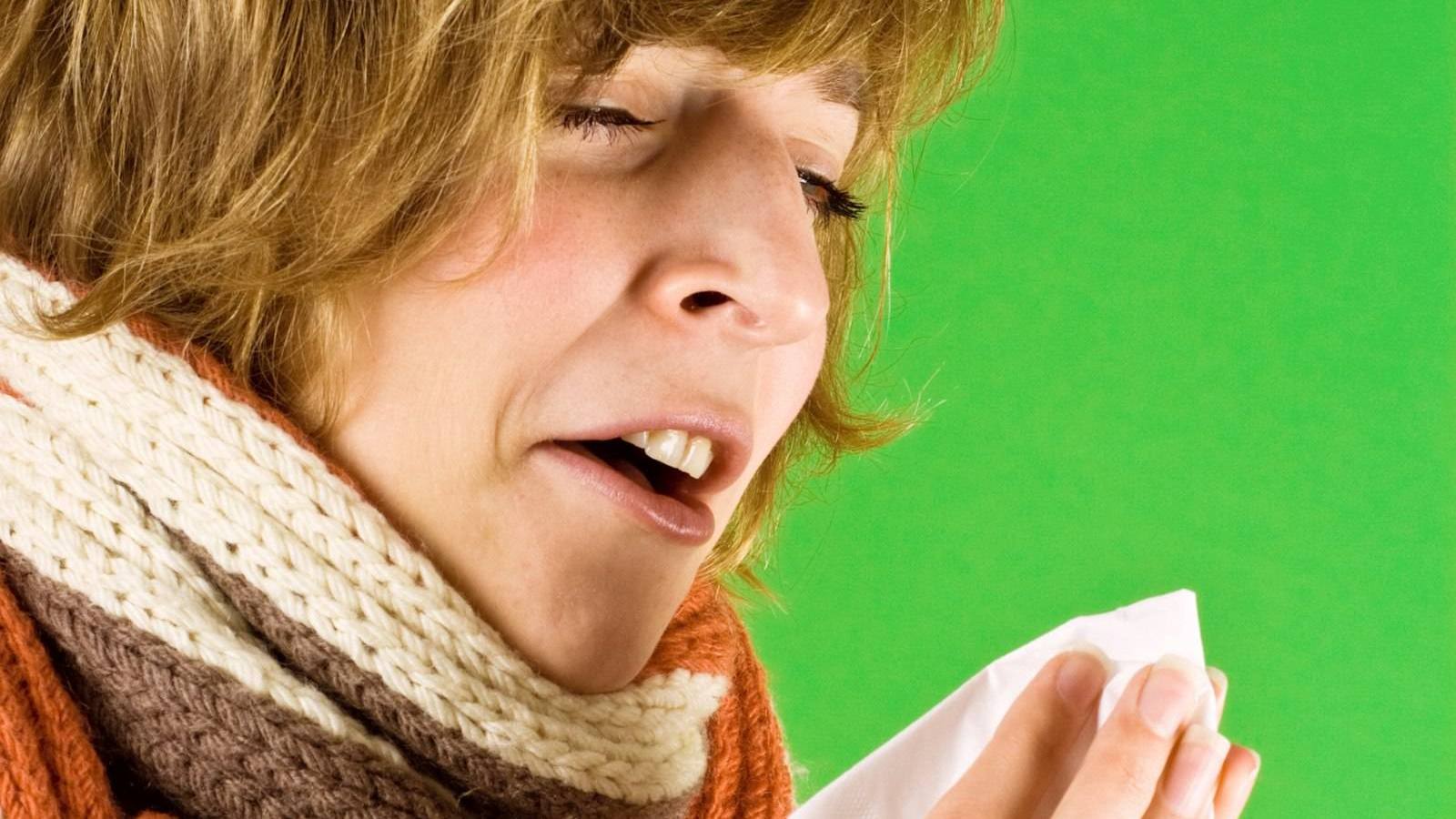 Woman in a scarf about to sneeze into a tissue